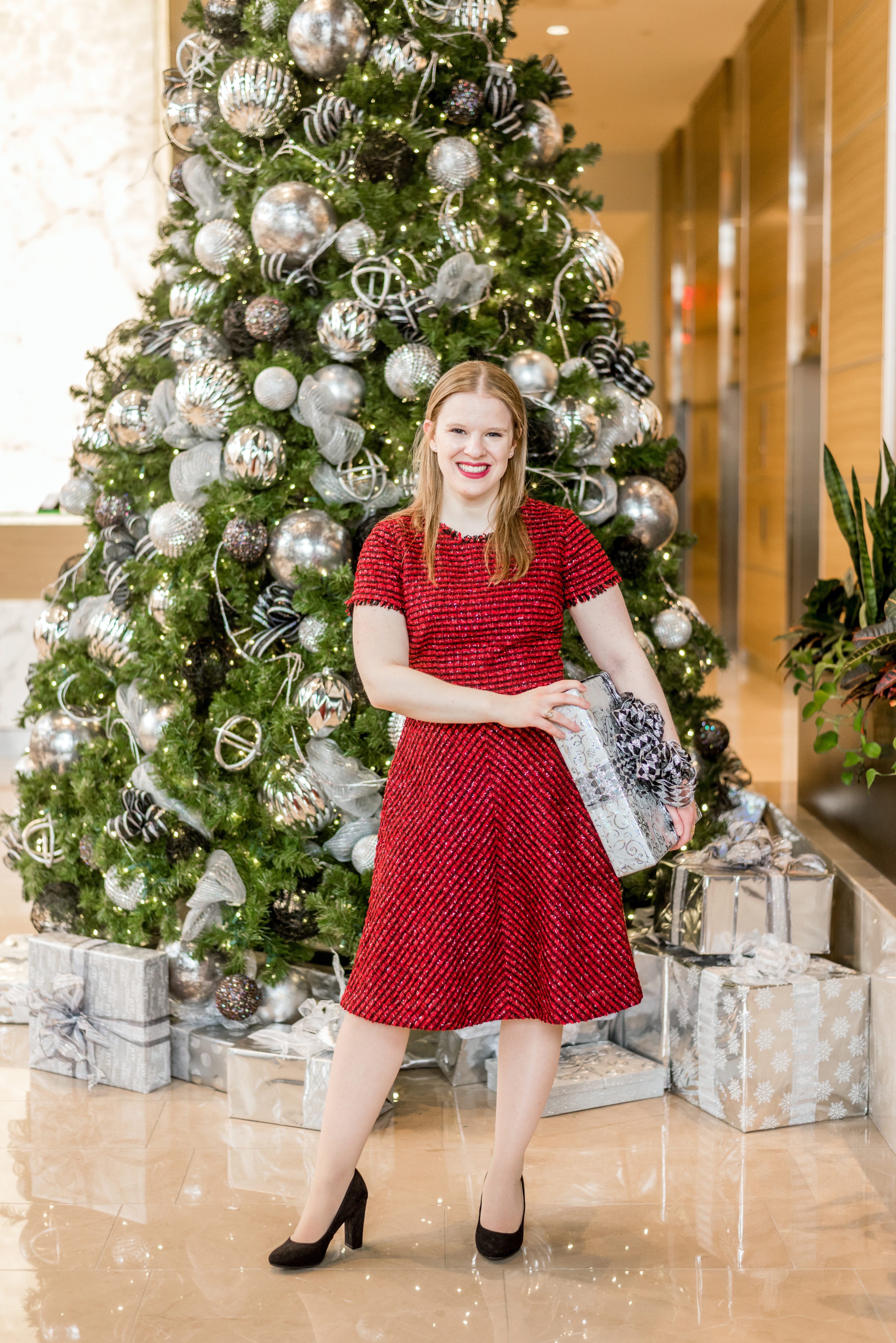 woman blogger in front of christmas tree wearing red festive dress