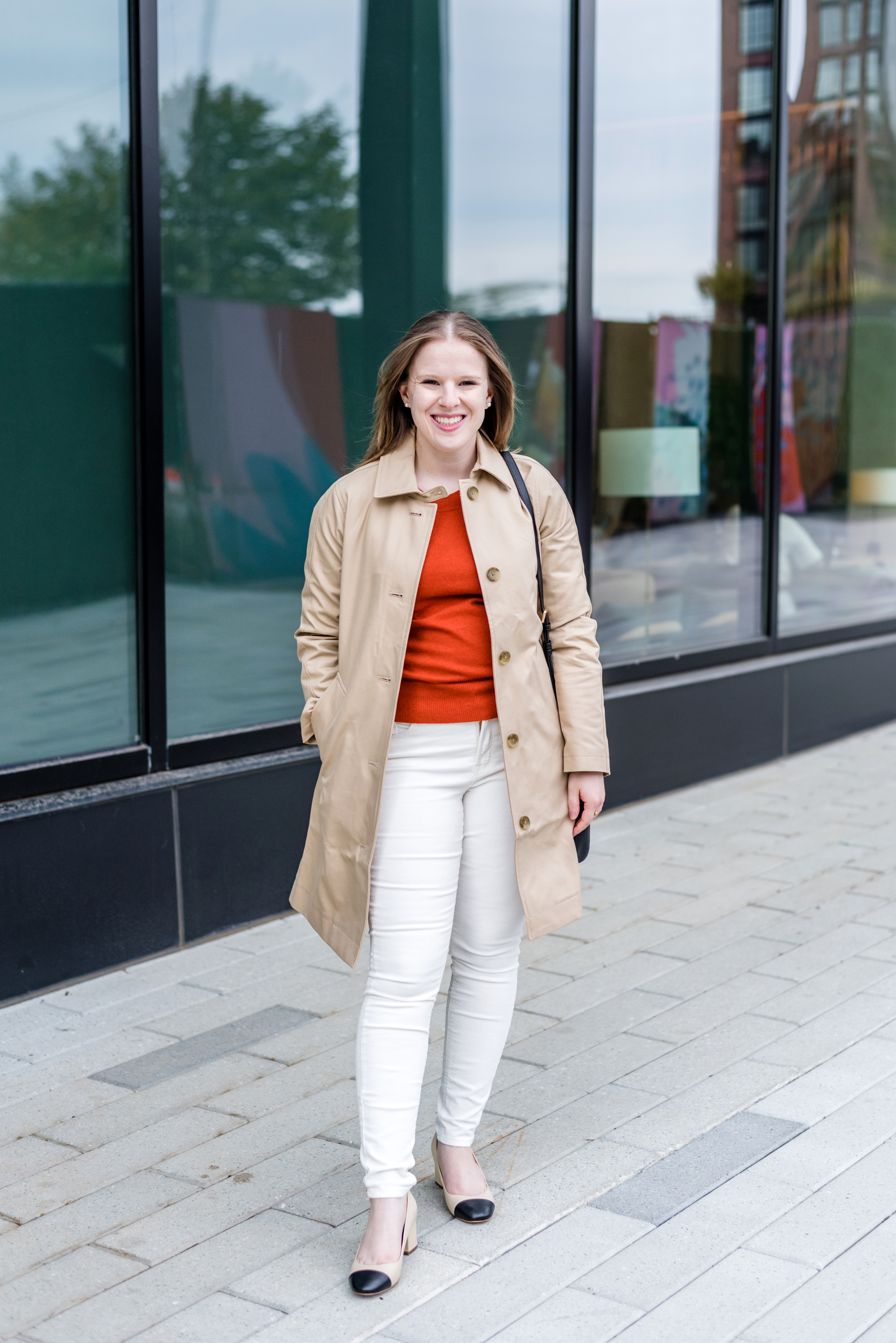 woman blogger wearing trench coat over white skinny jeans