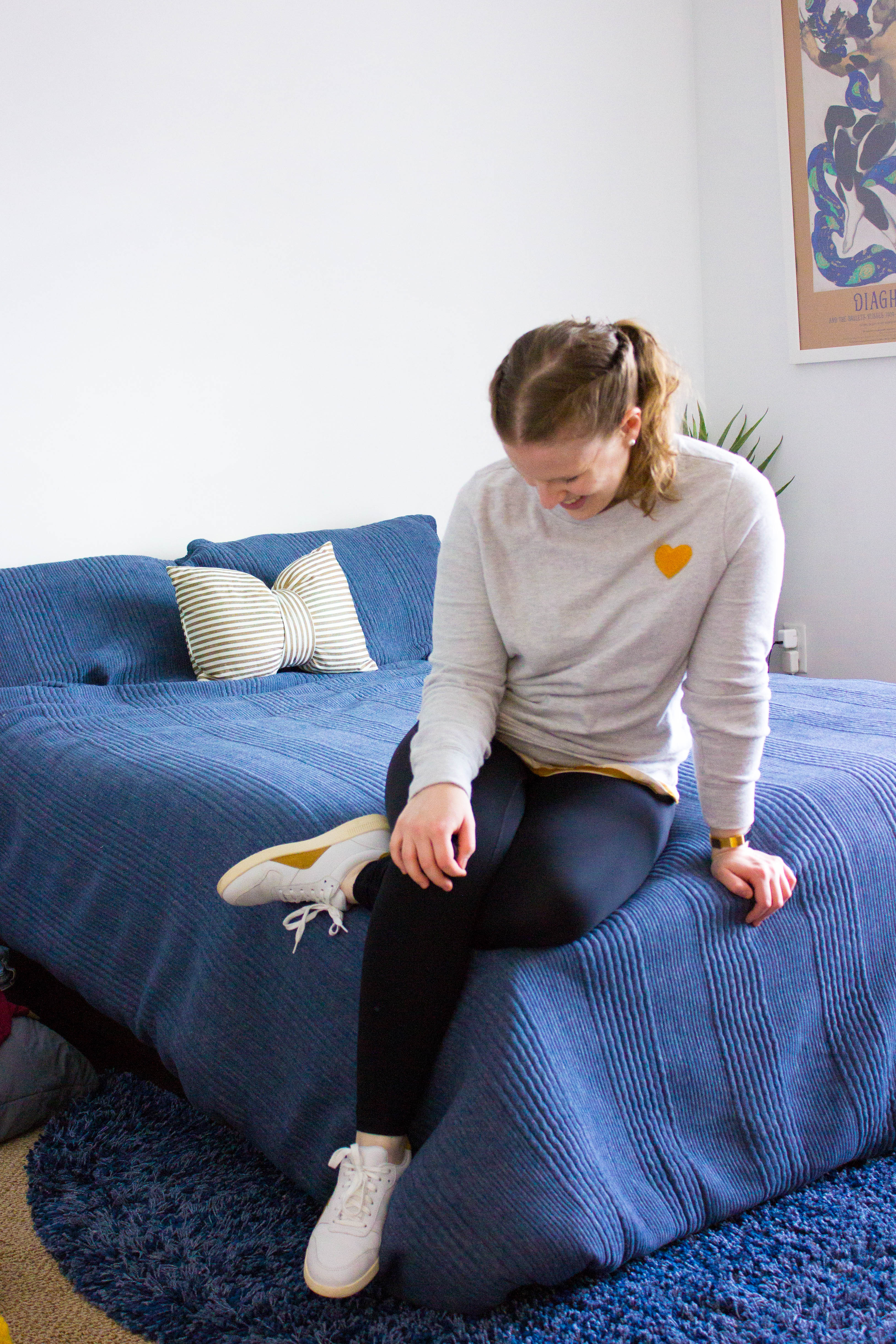 Woman wearing black everlane leggings and sitting on a bed for Casual Weekend Outfits