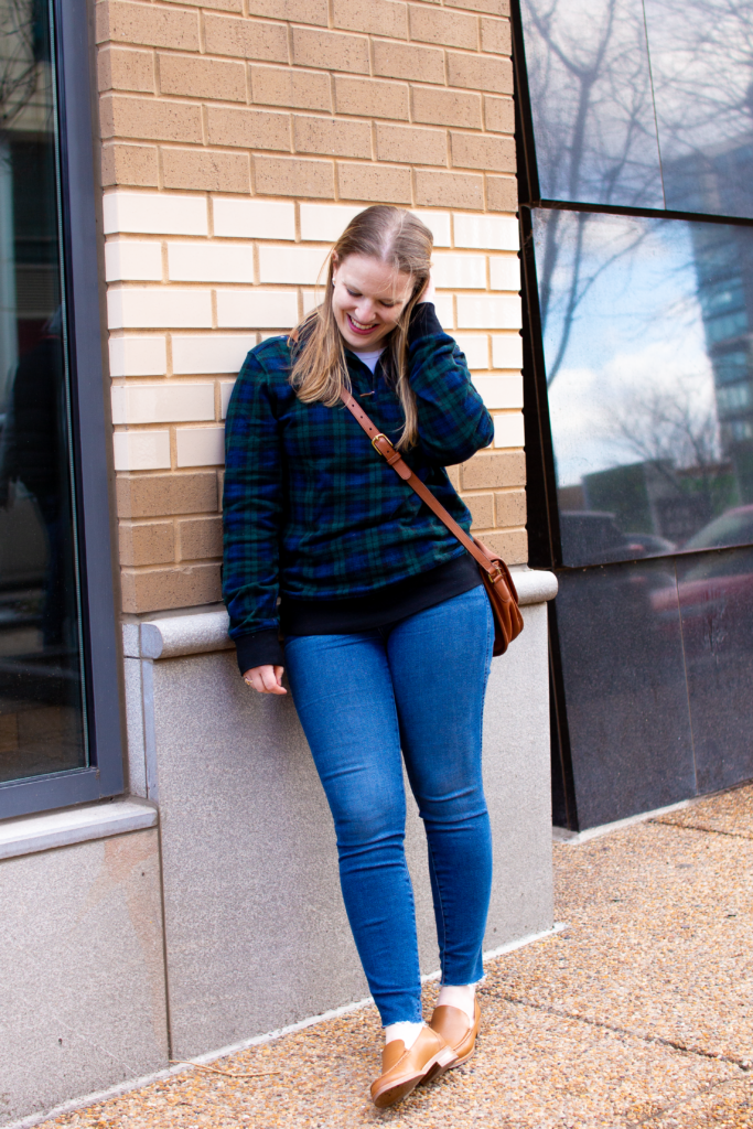 woman blogger leaning against brick wall wearing Ralph Lauren pullover and Everlane denim
