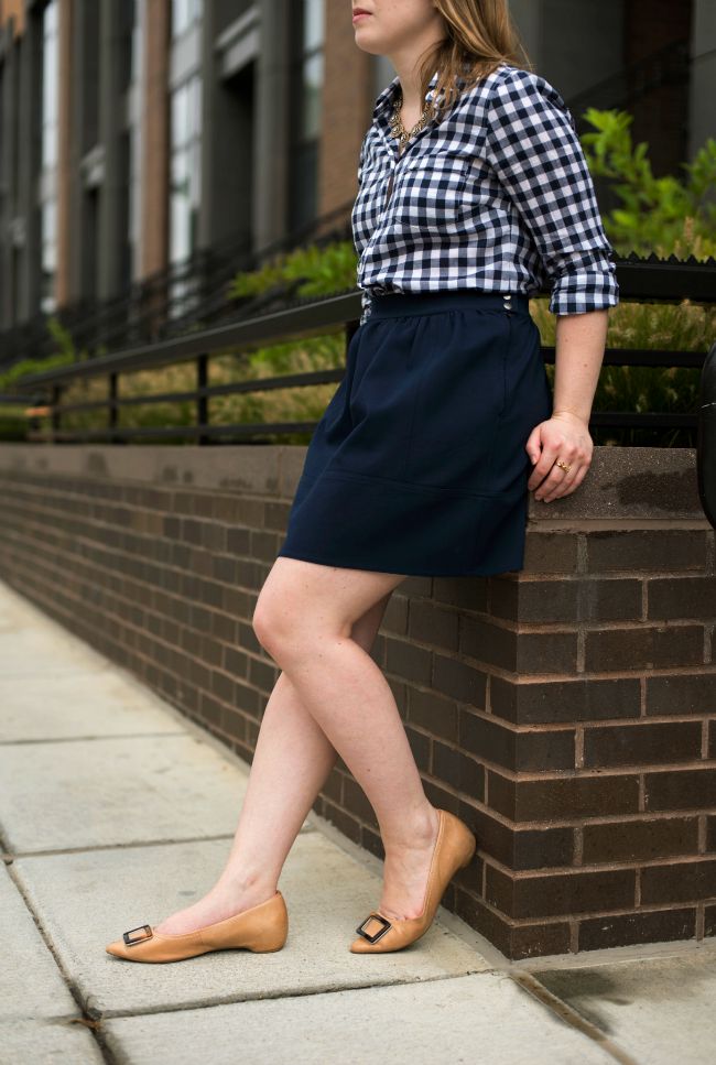 dc woman blogger wearing navy skirt, plaid button down shirt, and tan flats