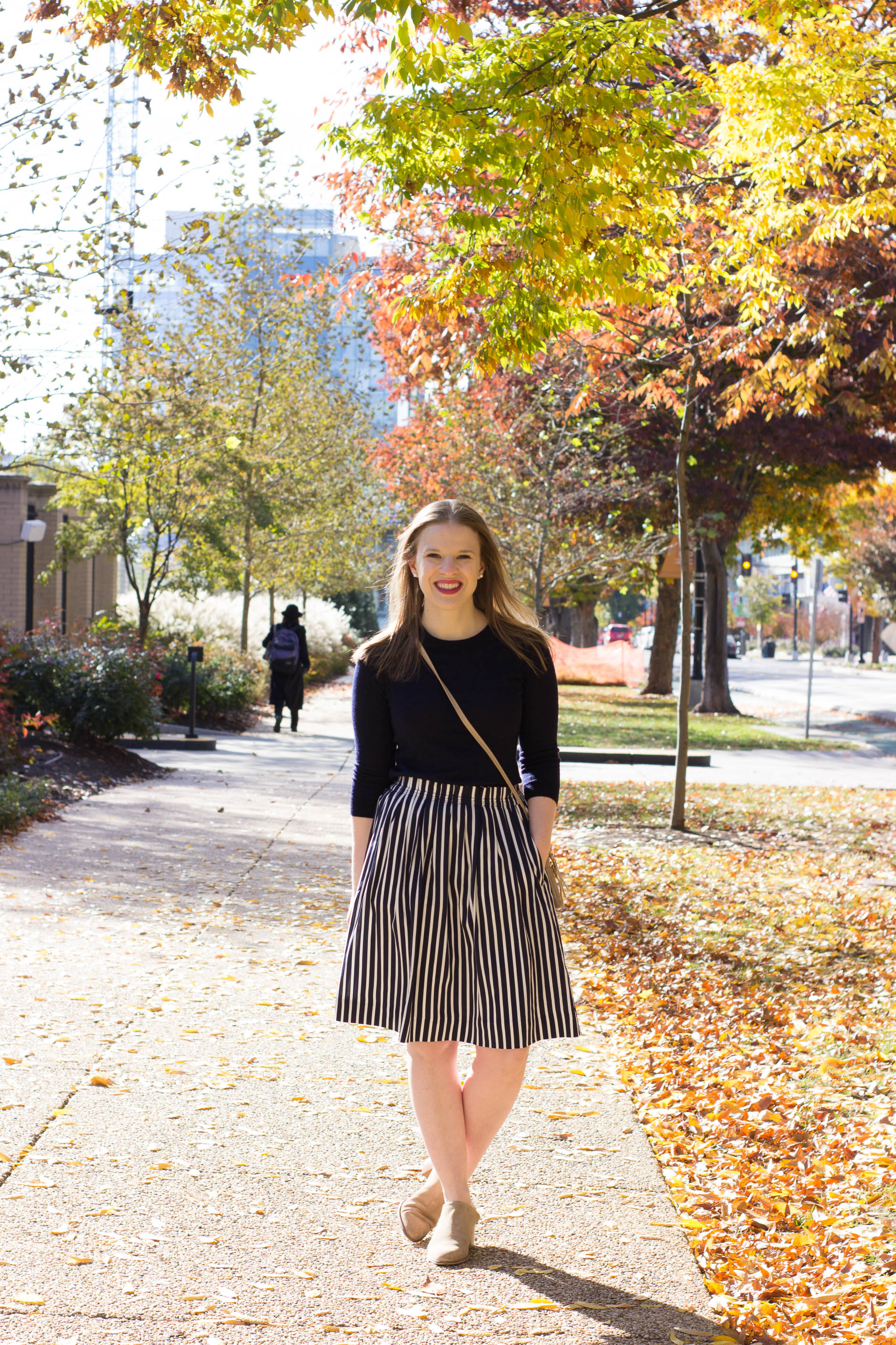 woman blogger wearing navy crew neck sweater and J.Crew striped midi skirt