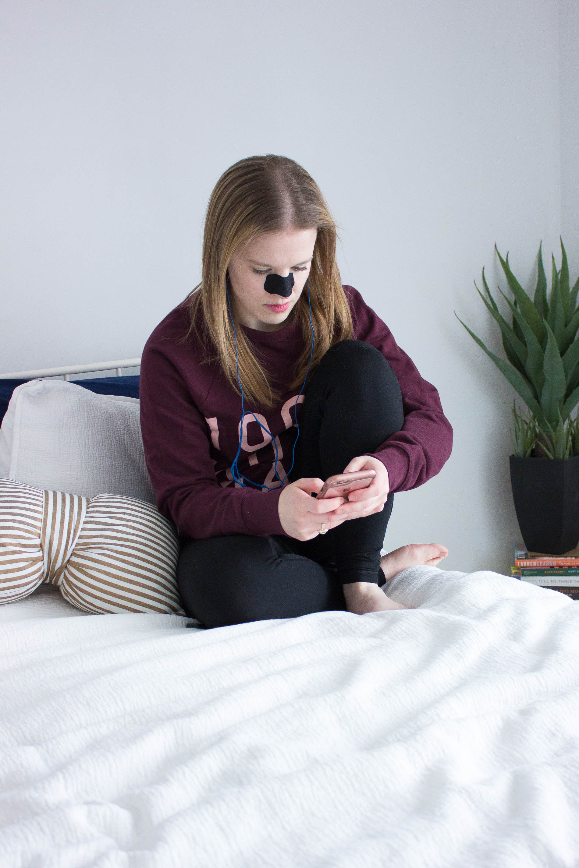 blogger woman looking at cell phone, woman with blackhead removal strip, skincare products