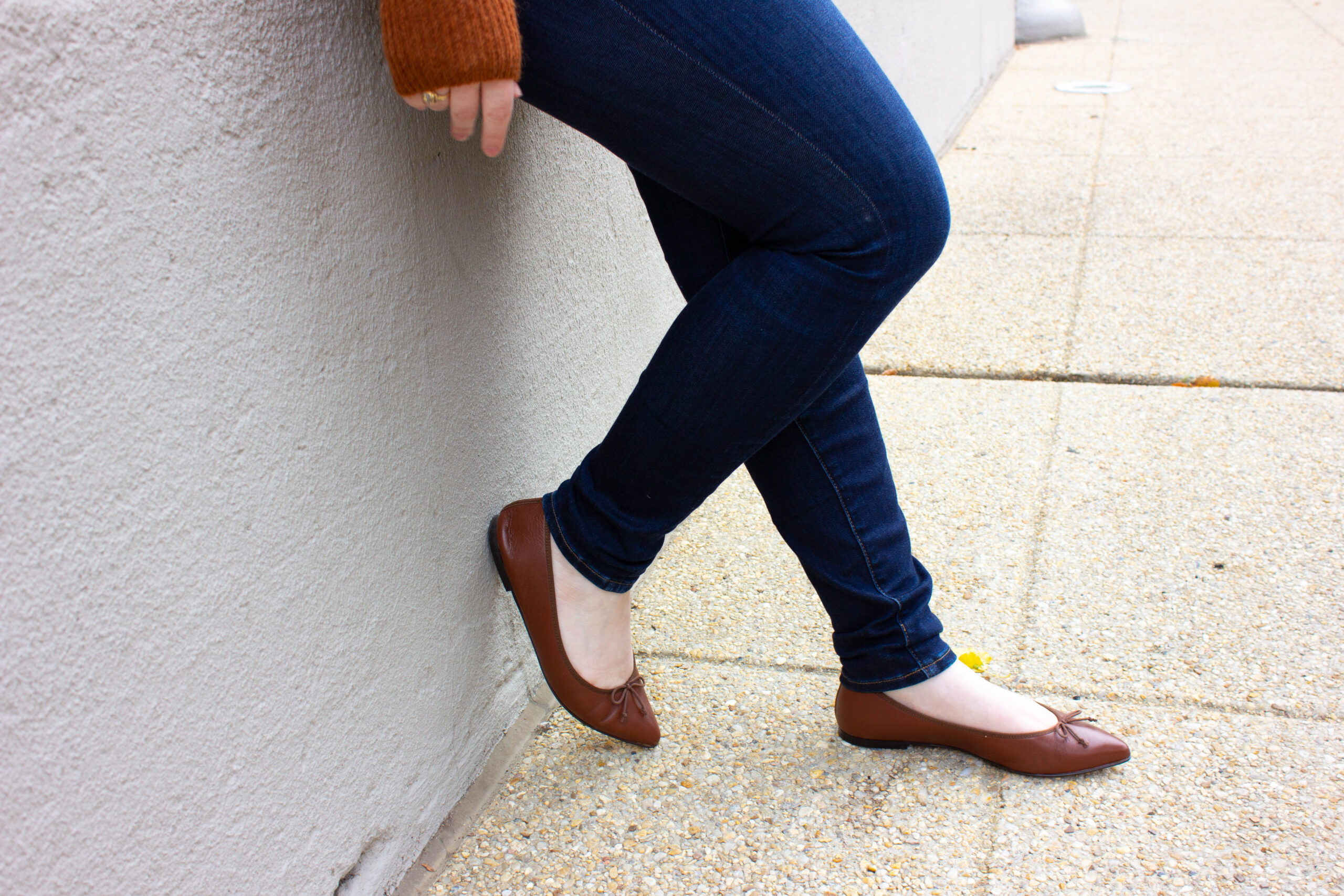 woman blogger wearing Madewell denim and brown J.Crew flats, leaning against wall